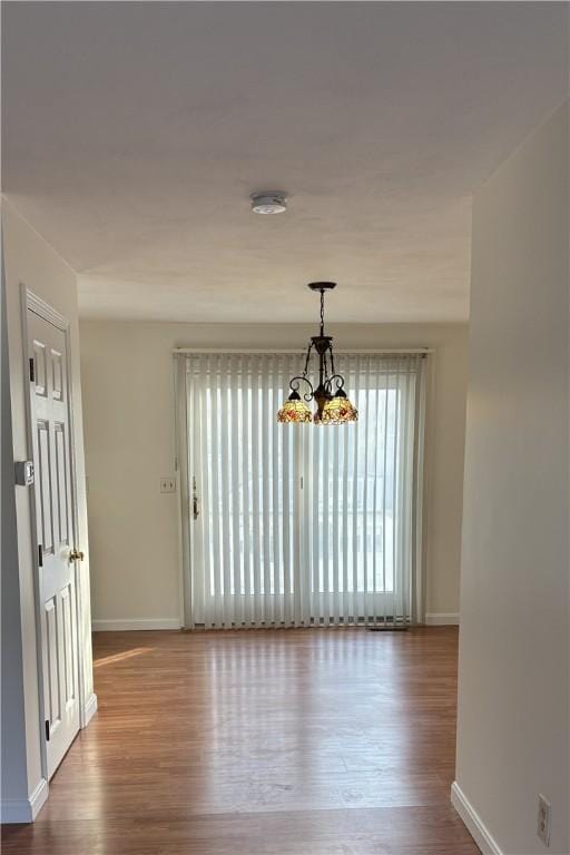 unfurnished dining area with hardwood / wood-style flooring and an inviting chandelier