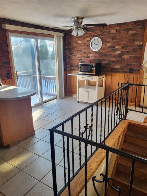 interior space featuring brick wall, tile patterned floors, and ceiling fan