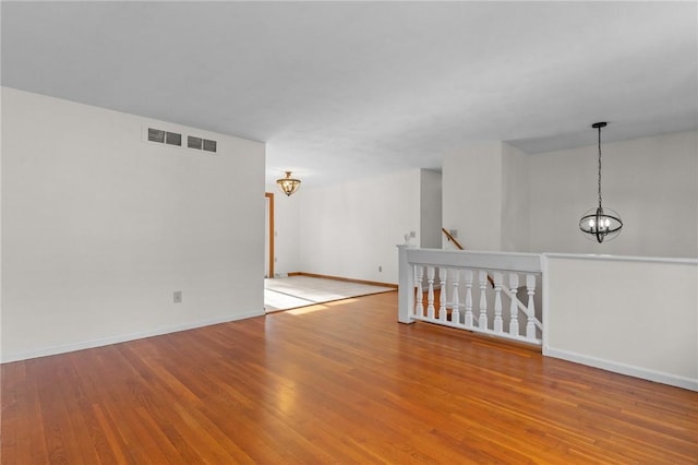 unfurnished room featuring a chandelier and light hardwood / wood-style flooring