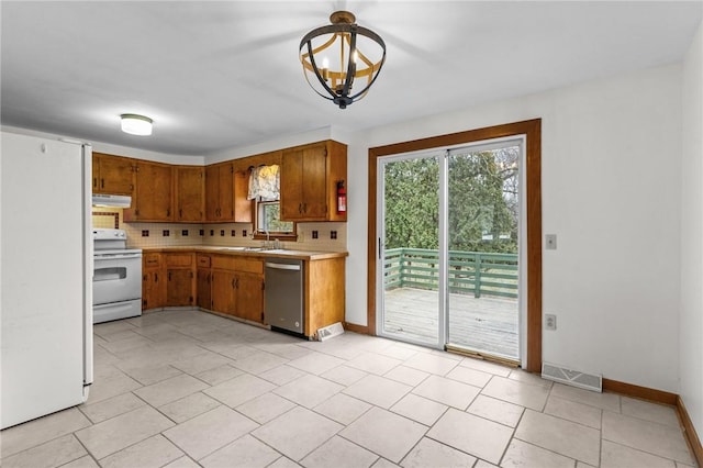 kitchen with an inviting chandelier, white appliances, sink, and decorative backsplash