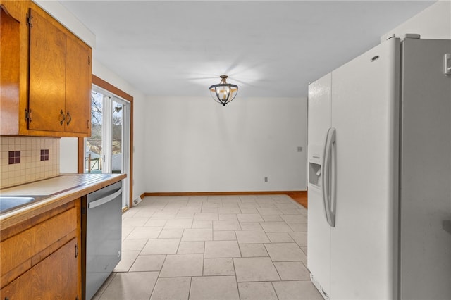 kitchen featuring white refrigerator with ice dispenser, stainless steel dishwasher, an inviting chandelier, and decorative backsplash