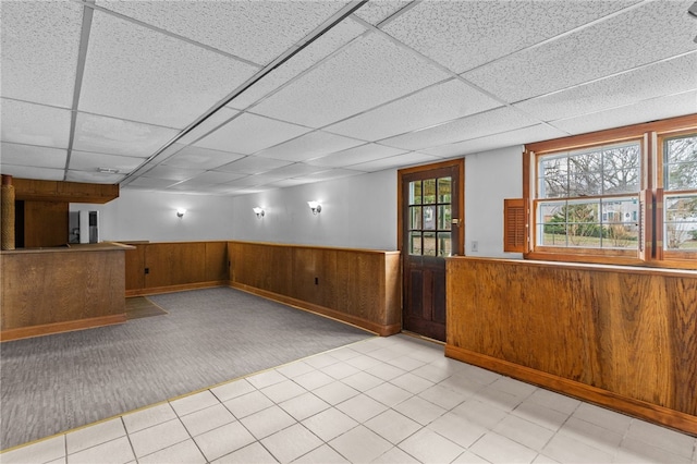 interior space featuring a drop ceiling and wood walls