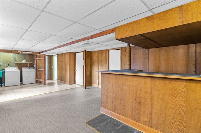 bar featuring washer and dryer, a drop ceiling, and wood walls