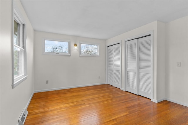 unfurnished bedroom featuring light hardwood / wood-style floors and two closets