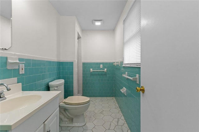 bathroom featuring tile patterned flooring, vanity, tile walls, and toilet