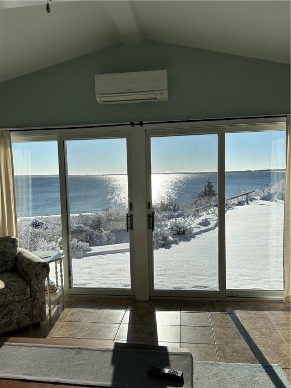 entryway featuring a water view, plenty of natural light, a wall mounted air conditioner, and lofted ceiling