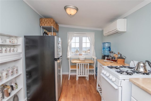 kitchen with stainless steel fridge, a wall mounted AC, white range with gas cooktop, and white cabinets