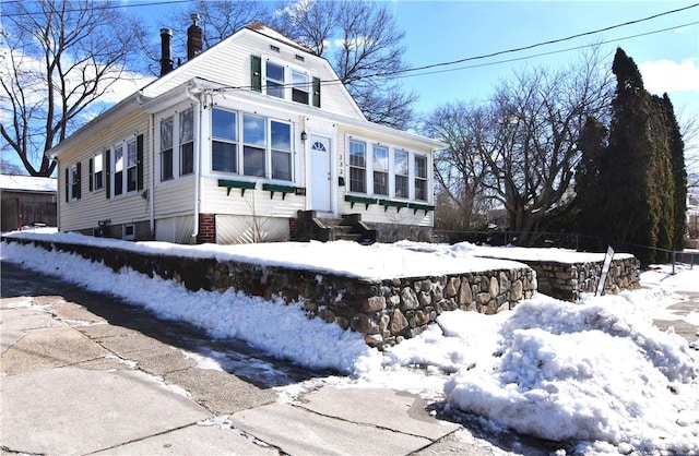 view of front of property with entry steps, driveway, and a chimney