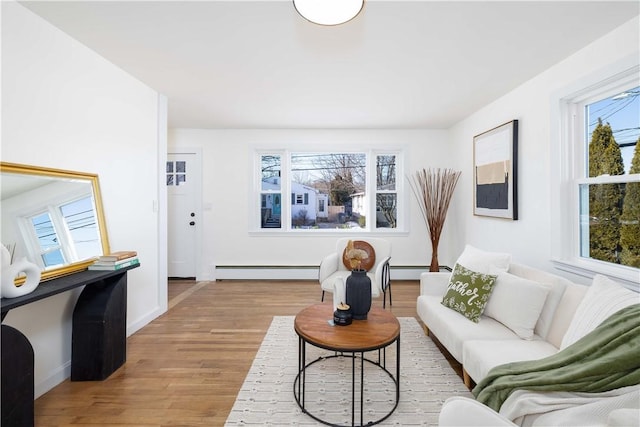 living room with a baseboard heating unit and light hardwood / wood-style flooring