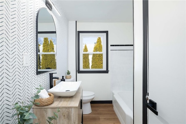 bathroom with wood-type flooring, vanity, a bathtub, and toilet