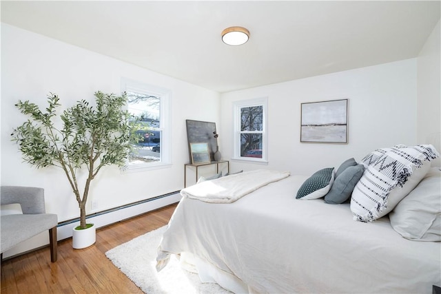 bedroom featuring a baseboard heating unit and hardwood / wood-style flooring