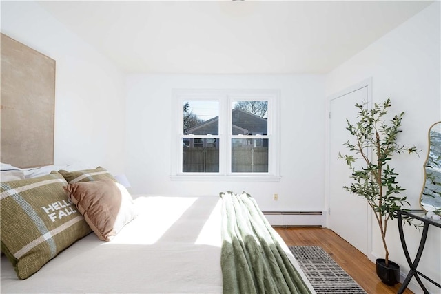 bedroom with baseboard heating and wood-type flooring