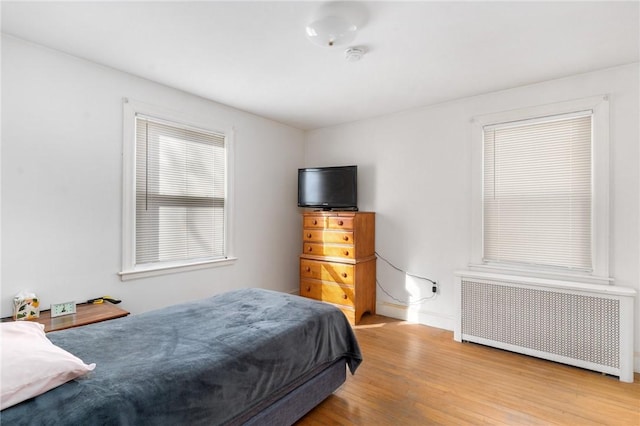 bedroom with radiator heating unit and wood-type flooring