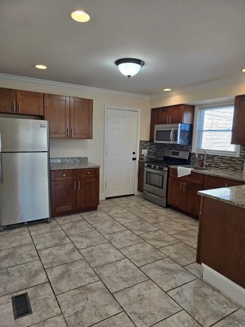 kitchen featuring crown molding, stainless steel appliances, tasteful backsplash, and stone counters