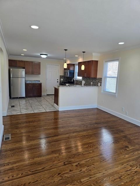 kitchen featuring stainless steel appliances, crown molding, pendant lighting, and decorative backsplash