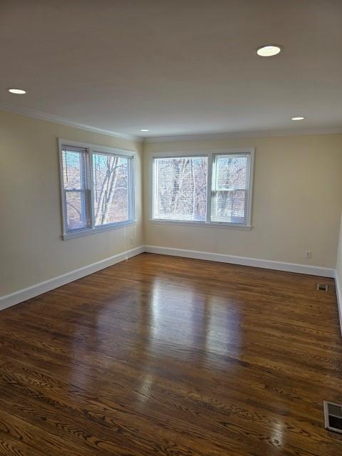 empty room with ornamental molding, plenty of natural light, and dark hardwood / wood-style floors