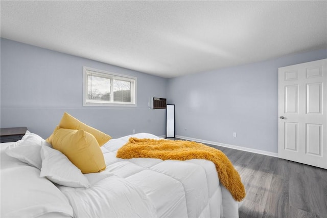 bedroom featuring dark hardwood / wood-style floors, a wall mounted air conditioner, and a textured ceiling