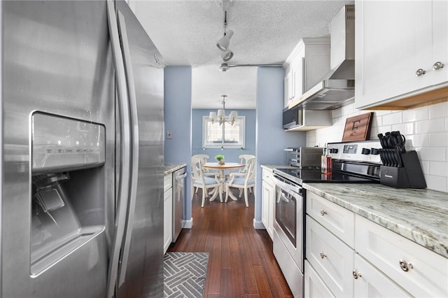 kitchen with wall chimney exhaust hood, decorative light fixtures, stainless steel appliances, decorative backsplash, and white cabinets