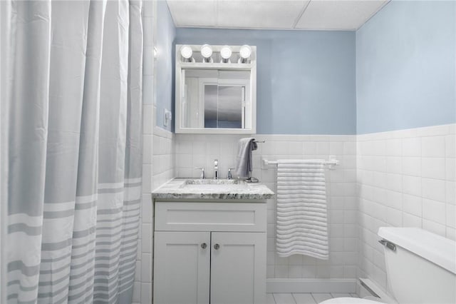 bathroom with vanity, tile walls, and toilet