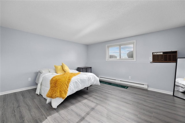 bedroom with a baseboard heating unit, a wall unit AC, a textured ceiling, and dark hardwood / wood-style flooring