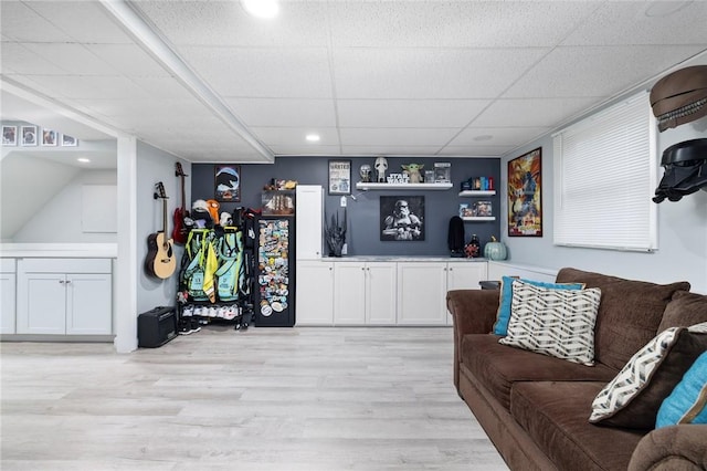 living room featuring a drop ceiling and light hardwood / wood-style flooring