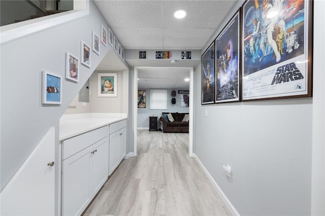 corridor featuring a drop ceiling and light wood-type flooring