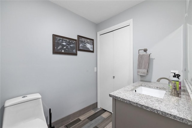 bathroom featuring vanity, hardwood / wood-style flooring, and toilet