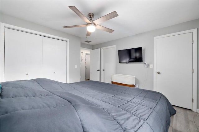 bedroom with ceiling fan, a closet, and light hardwood / wood-style flooring