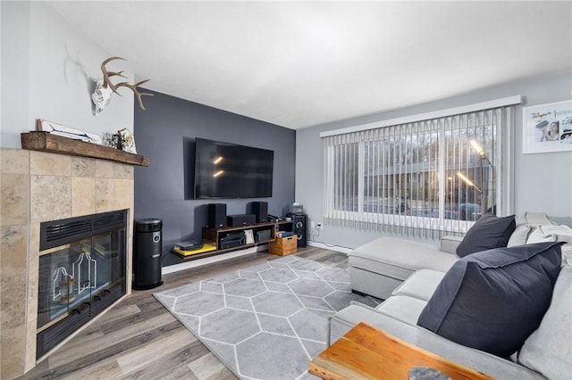 living room with a tiled fireplace and hardwood / wood-style flooring