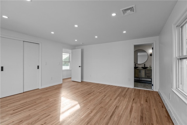 unfurnished bedroom featuring connected bathroom and light wood-type flooring