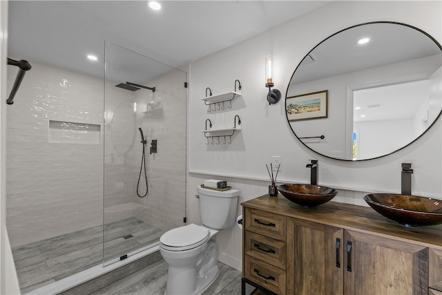 bathroom featuring vanity, hardwood / wood-style floors, toilet, and tiled shower