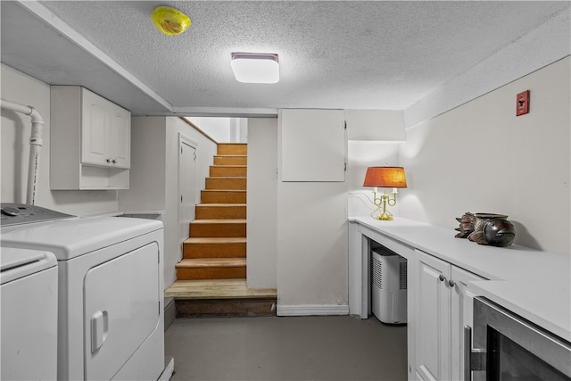 laundry room with independent washer and dryer, cabinets, a textured ceiling, and wine cooler