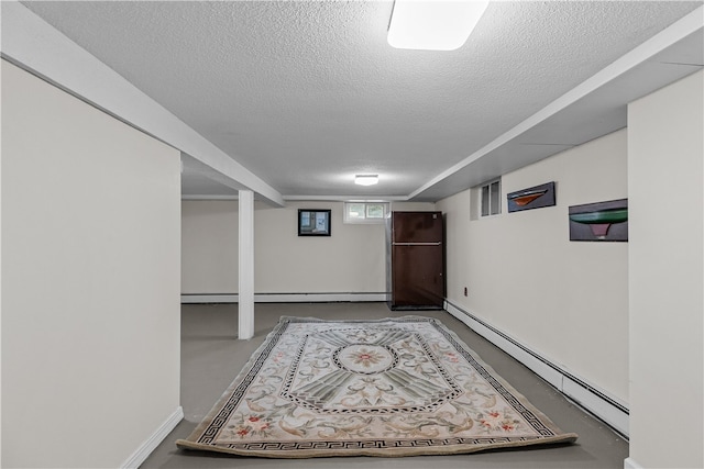 basement with fridge, a textured ceiling, and baseboard heating