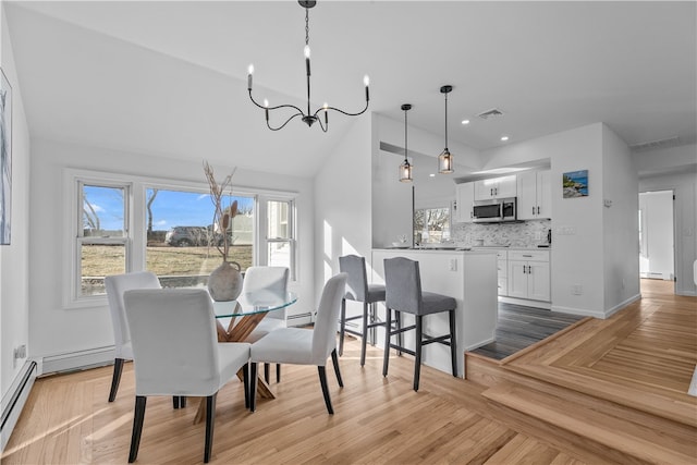 dining space with an inviting chandelier, a baseboard radiator, and light wood-type flooring