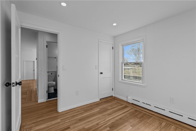 unfurnished bedroom featuring baseboard heating and light hardwood / wood-style floors