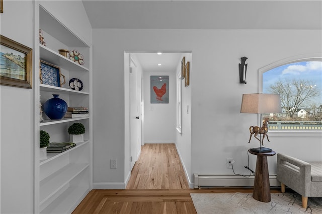 corridor featuring built in shelves, light hardwood / wood-style floors, and a baseboard heating unit