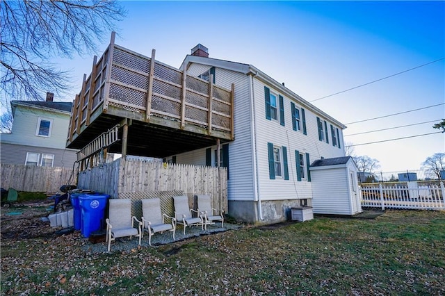 back of house with a wooden deck, a storage unit, and a lawn