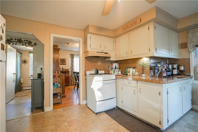 kitchen with white range with gas cooktop, a baseboard heating unit, tasteful backsplash, and white cabinets