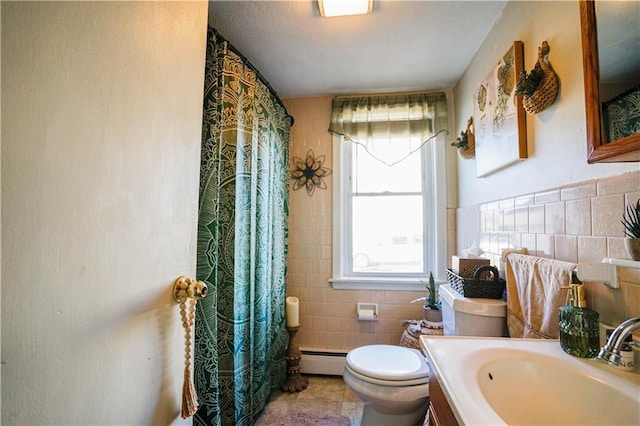 bathroom with vanity, tile walls, baseboard heating, and toilet