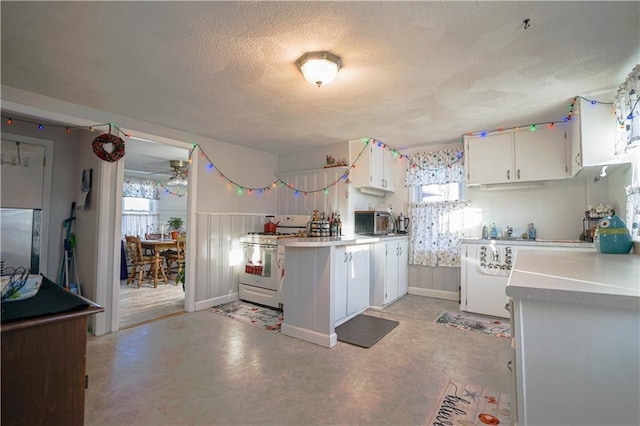 kitchen featuring a textured ceiling, kitchen peninsula, gas range gas stove, and white cabinets