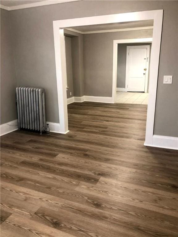 spare room with crown molding, dark hardwood / wood-style floors, and radiator heating unit