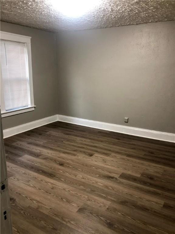 spare room featuring dark wood-type flooring and a textured ceiling