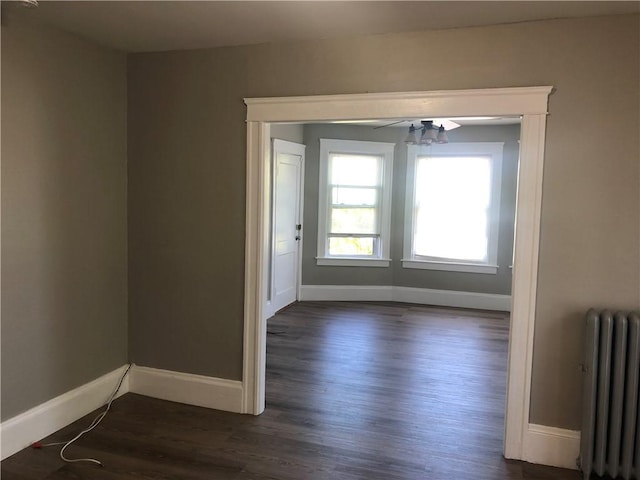 unfurnished room featuring radiator, dark wood-type flooring, and ceiling fan