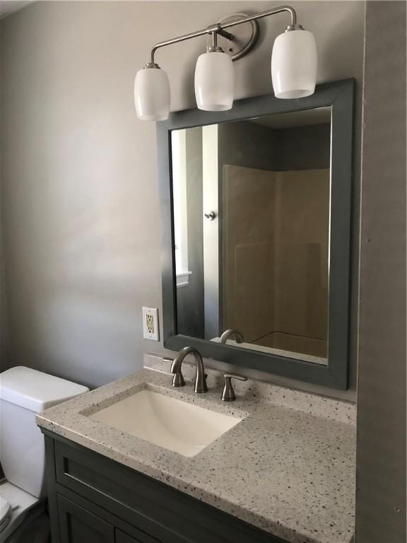 bathroom with walk in shower, vanity, and toilet