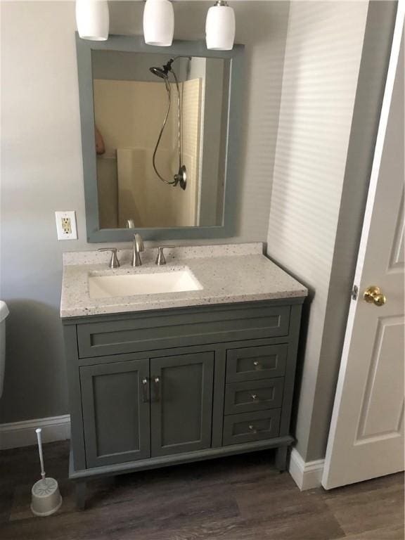 bathroom with hardwood / wood-style flooring, vanity, and a shower