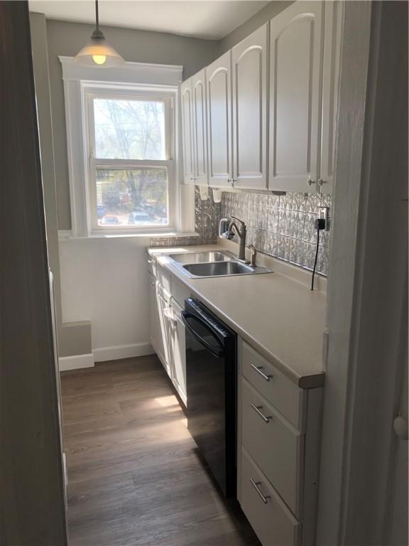 kitchen featuring sink, decorative light fixtures, dark hardwood / wood-style flooring, dishwasher, and white cabinets