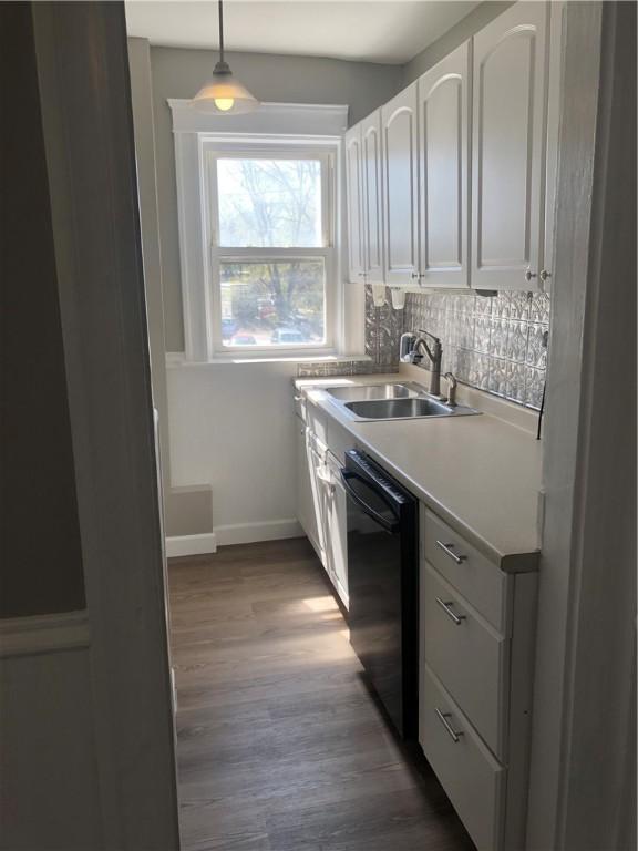 kitchen with sink, dishwasher, hanging light fixtures, white cabinets, and decorative backsplash