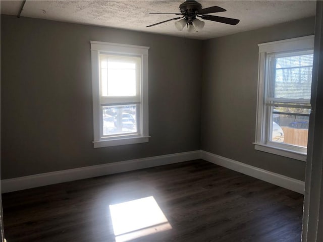 spare room featuring ceiling fan, dark hardwood / wood-style flooring, a textured ceiling, and a wealth of natural light