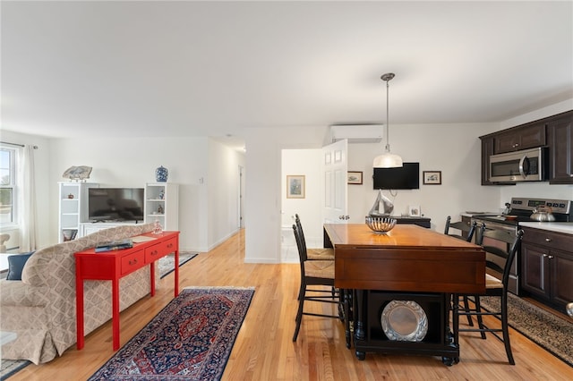 dining space featuring a wall mounted air conditioner and light hardwood / wood-style flooring