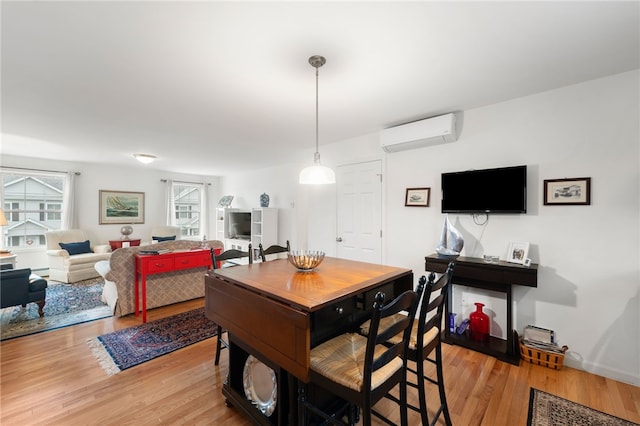 dining space with an AC wall unit and light hardwood / wood-style floors